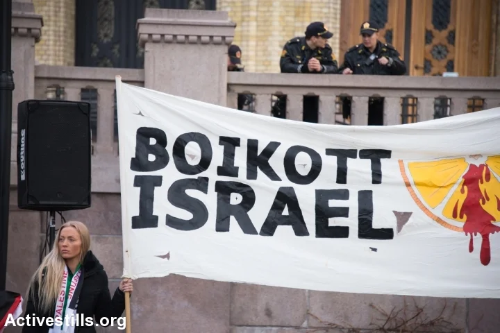 Police watch from above as solidarity activists hold a banner reading “Boycott Israel” during a protest in front of the Norwegian Parliament building, Stortinget, Oslo, March 30, 2015. (photo: Ryan Rodrick Beiler/Activestills.org)
